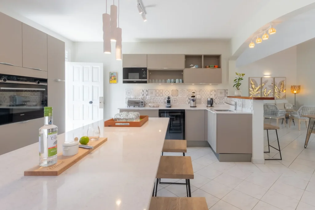 Cuisine Villa Bel Embrun Une cuisine moderne avec un îlot central, des chaises en bois et un éclairage chaleureux.