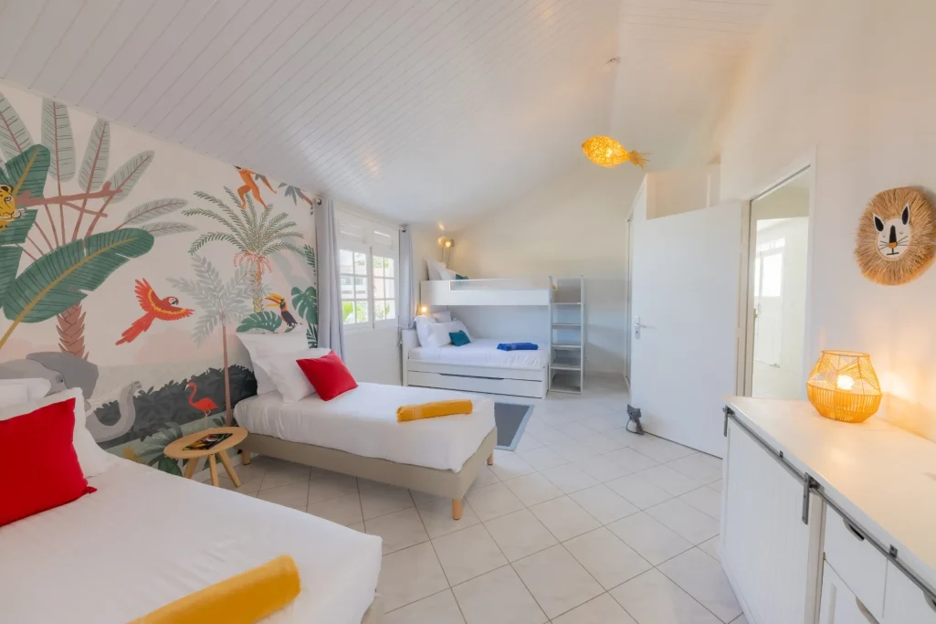 Chambre Jungle Villa Bel Embrun Chambre pour enfants composée de quatre lits, décor tropical et ambiance accueillante.