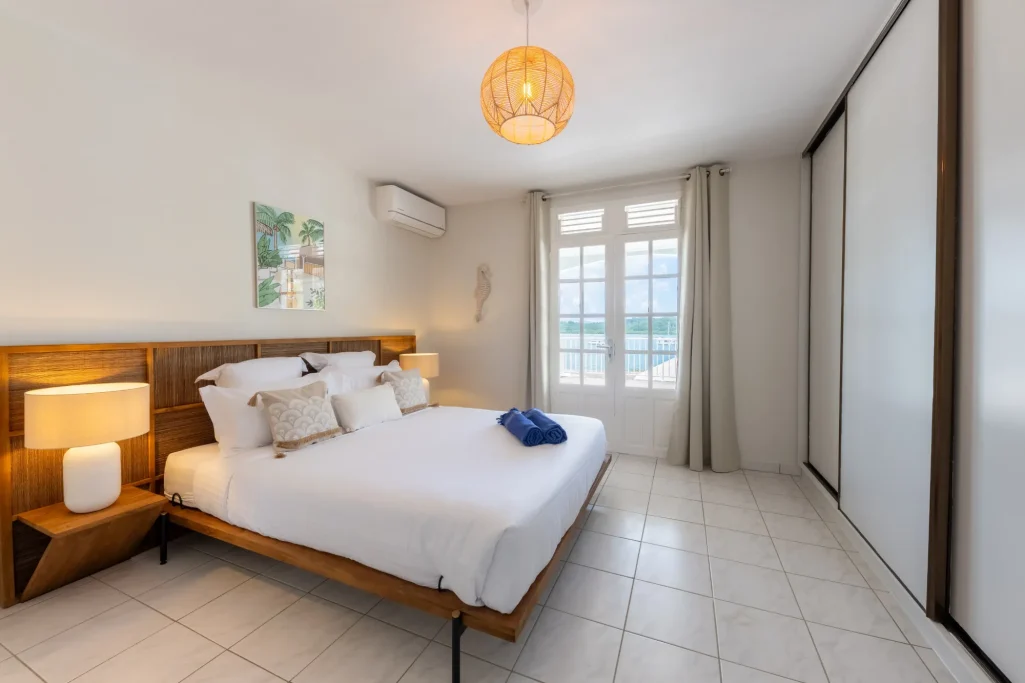 Chambre Villa Bel Embrun Chambre lumineuse avec lit double, tapis, et grandes fenêtres. Décoration moderne et épurée.