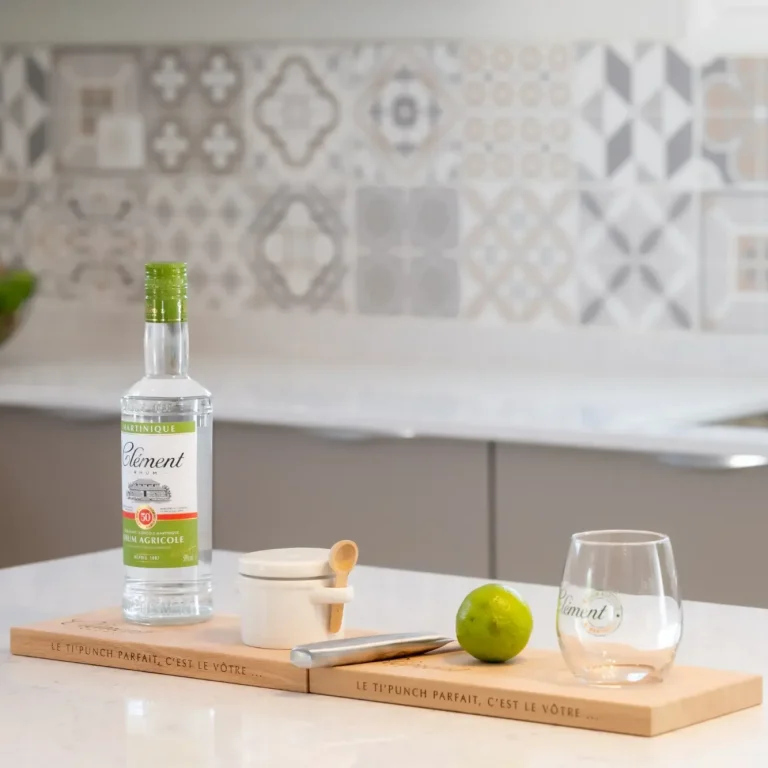 Cadeau de bienvenue Bouteille de rhum, citron vert, verre et ustensiles sur une planche en bois.