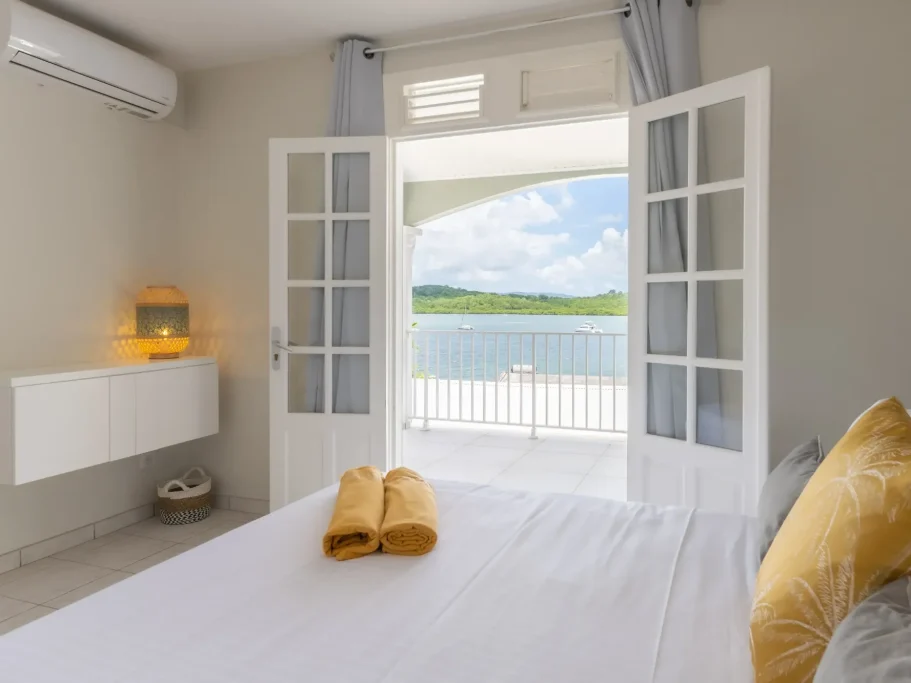 Chambre Sunset Chambre lumineuse avec fenêtres ouvertes donnant sur une vue de la mer.